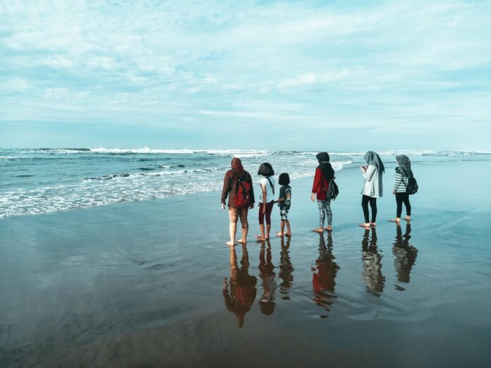 Rodzina spaceruje po plaży Pangandaran w Indonezji o zachodzie słońca