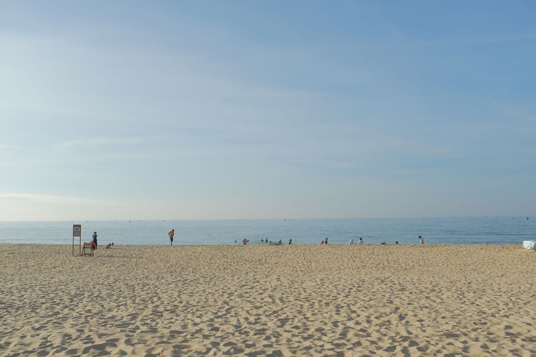 Plaża w Binh Thuan w pełnym słońcu, ludzie spacerują nad spokojnym morzem