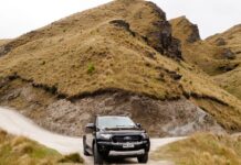 SUV na szutrowej drodze w górskim krajobrazie Coronet Peak w Nowej Zelandii