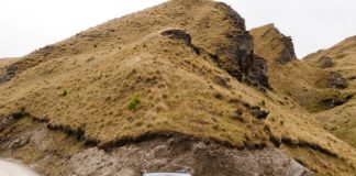 SUV na szutrowej drodze w górskim krajobrazie Coronet Peak w Nowej Zelandii