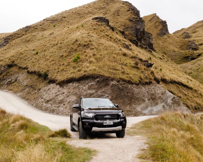 SUV na szutrowej drodze w górskim krajobrazie Coronet Peak w Nowej Zelandii SUV na szutrowej drodze w górskim krajobrazie Coronet Peak w Nowej Zelandii