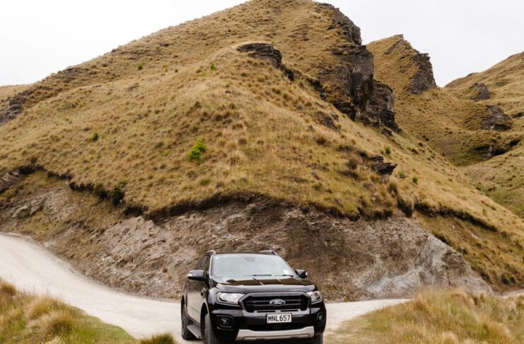 SUV na szutrowej drodze w górskim krajobrazie Coronet Peak w Nowej Zelandii